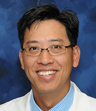 A man in glasses and a jacket standing up.